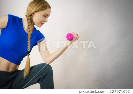 Teenage woman working out at home with dumbbell Teenage woman working out at home with dumbbell 127971692