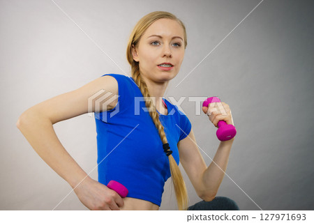 Teenage woman working out at home with dumbbell 127971693