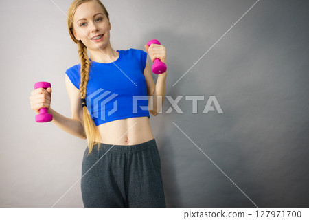 Teenage woman working out at home with dumbbell Teenage woman working out at home with dumbbell 127971700