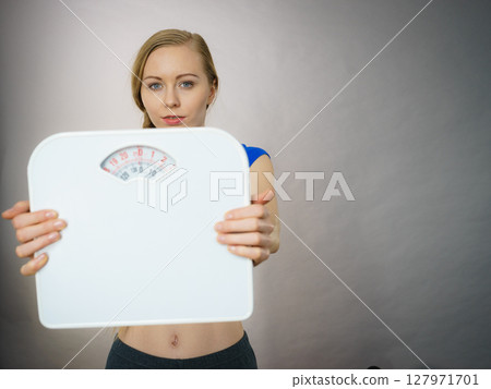 Teenage woman holding bathroom scale machine Teenage woman holding bathroom scale machine 127971701