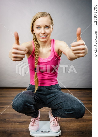 Teenage woman on bathroom scale machine Teenage woman on bathroom scale machine 127971706