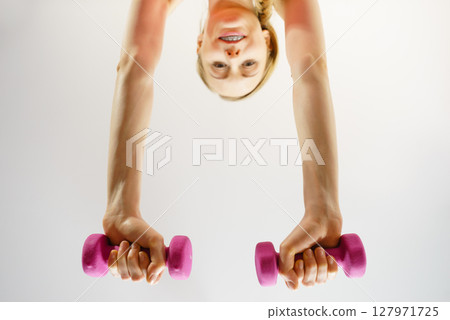 Teenage woman working out at home with dumbbell 127971725