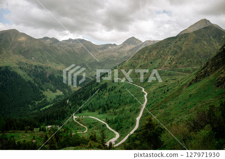 Winding mountain road through lush green valley in the Austrian Alps Winding mountain road through lush green valley in the Austrian Alps 127971930