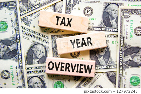 Tax year overview symbol. Concept words Tax year overview on beautiful wooden blocks. Dollar bills. Beautiful background from dollar bills. Business tax year overview concept. Copy space. Tax year overview symbol. Concept words Tax year overview on beautiful wooden blocks. Dollar bills. Beautiful background from dollar bills. Business tax year overview concept. Copy space. 127972243
