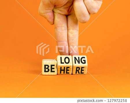 Belonging and belong symbol. Concept words Be here Belong on beautiful wooden block. Beautiful orange background Businessman hand. Business motivational belonging and belong concept. Copy space. 127972258