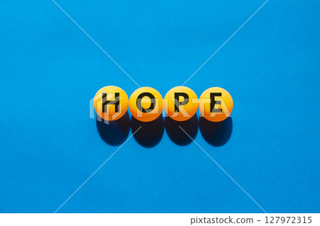 Hope symbol. Concept word Hope on beautiful yellow ping pong balls. Beautiful blue table blue background. Business, lifestyle, support and hope concept. Copy space. Hope symbol. Concept word Hope on beautiful yellow ping pong balls. Beautiful blue table blue background. Business, lifestyle, support and hope concept. Copy space. 127972315