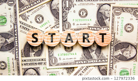 Start symbol. Concept word Start on beautiful wooden circles. Beautiful dollar bills. Beautiful background from dollar bills. Business lifestyle start concept. Copy space. Start symbol. Concept word Start on beautiful wooden circles. Beautiful dollar bills. Beautiful background from dollar bills. Business lifestyle start concept. Copy space. 127972336