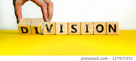 Division or vision symbol. Businessman turns wooden cubes and changes the word 'division' to 'vision'. Beautiful yellow table, white background. Business, division or vision concept. Copy space. 127972352