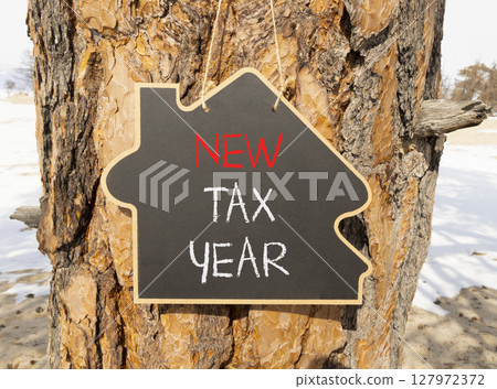 New tax year symbol. Concept words New tax year on beautiful black yellow blackboard. Beautiful old wood and sand background. Business new tax year concept. Copy space. New tax year symbol. Concept words New tax year on beautiful black yellow blackboard. Beautiful old wood and sand background. Business new tax year concept. Copy space. 127972372