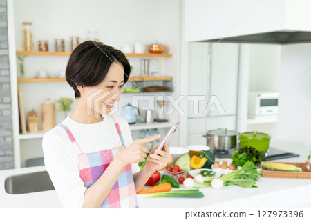 在廚房中使用智能手機的中年家庭主婦 127973396