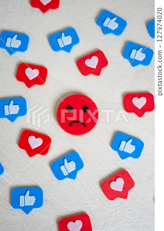 Sad face surrounded by likes and hearts from social networks. Chasing likes does not make you happy. Internet addiction, doomscrolling. Endorphin addiction. Emotional burnout in digital culture Sad face surrounded by likes and hearts from social networks. Chasing likes does not make you happy. Internet addiction, doomscrolling. Endorphin addiction. Emotional burnout in digital culture 127974020