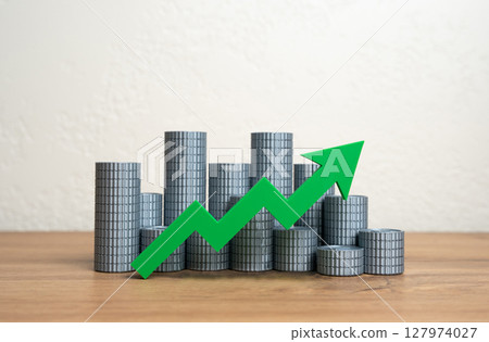 Stacks of money coins and a green arrow pointing up. Increasing income and wealth. Growth of the money supply. Increasing the economy. Wealth growth, capital accumulation, or a booming economy. 127974027