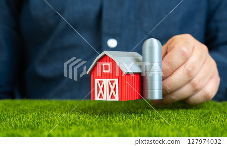 A man builds a farm on a plot of land. Construction and building. Development of farms. Land ownership, countryside migration. Rural revitalization, sustainable development, and self-sufficiency. 127974032