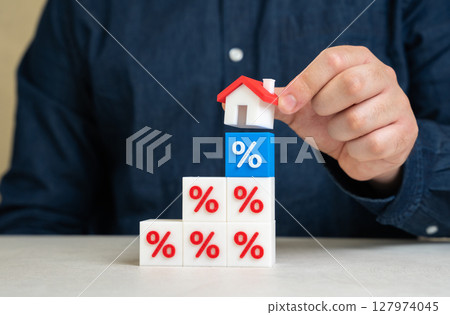 Man puts house on interest rate blocks. Mortgage flexibility, banking relief programs, loan restructuring. Credit holidays can ease financial strain during crises or inflationary periods. 127974045