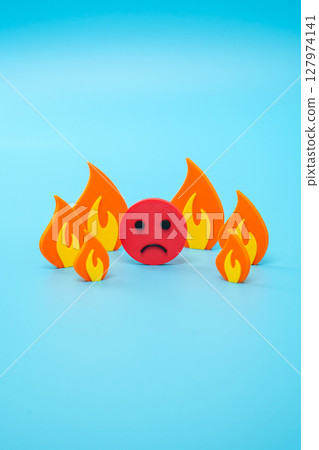 Sad face surrounded by fire, metaphor. Strong stress and anxious situation. Emotional burnout, chronic stress, and social overload in high-pressure environments. Personal crises, mental health Sad face surrounded by fire, metaphor. Strong stress and anxious situation. Emotional burnout, chronic stress, and social overload in high-pressure environments. Personal crises, mental health 127974141