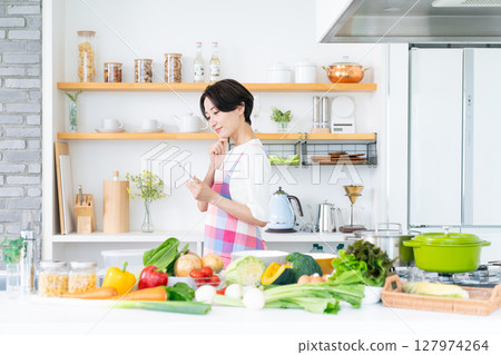 Middle woman using a tablet in the kitchen 127974264