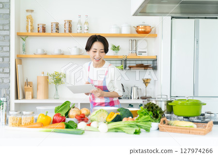 Middle woman using a tablet in the kitchen Middle woman using a tablet in the kitchen 127974266