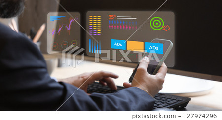 Businessman using smartphone and futuristic monitor to manage marketing statistics and ads 127974296