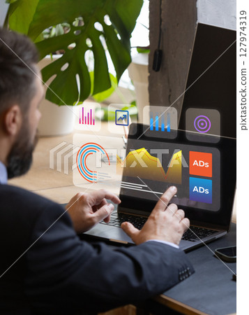 Executive managing digital advertising metrics using futuristic holographic laptop interface Executive managing digital advertising metrics using futuristic holographic laptop interface 127974319