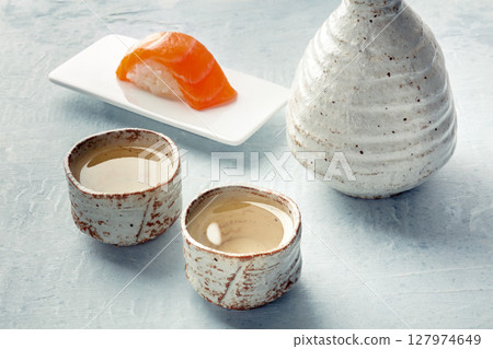 Sake in a pitcher and ochoko, traditional cup, with salmon nigiri Sake in a pitcher and ochoko, traditional cup, with salmon nigiri 127974649