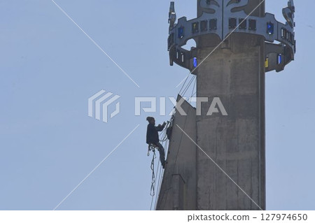 A craftsman repairs the tower of a modern church. A tinsmith repairs the tower of a modern building. The concept of working at heights and work safety A craftsman repairs the tower of a modern church. A tinsmith repairs the tower of a modern building. The concept of working at heights and work safety 127974650