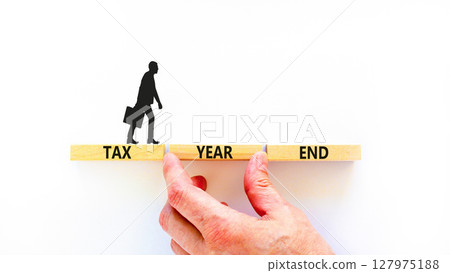 Tax year end symbol. Concept words Tax year end on beautiful wooden blocks. Beautiful white background. Businessman hand. Business tax year end concept. Copy space. Tax year end symbol. Concept words Tax year end on beautiful wooden blocks. Beautiful white background. Businessman hand. Business tax year end concept. Copy space. 127975188