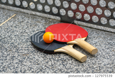 Rackets for table tennis in park close up. Red black ping pong table tennis paddles and yellow ball 127975539