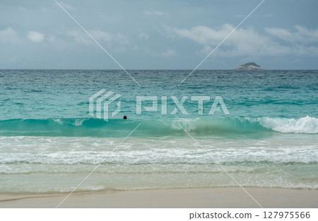 Tropical turquoise wave rolling to sandy beach in Seychelles, with foamy surf, calm horizon Tropical turquoise wave rolling to sandy beach in Seychelles, with foamy surf, calm horizon 127975566