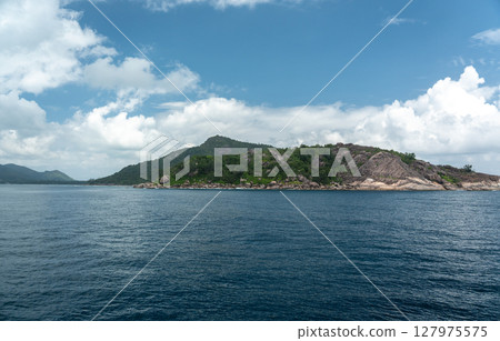Tropical view of Praslin Island from a ferry in Seychelles, featuring clear ocean, blue sky Tropical view of Praslin Island from a ferry in Seychelles, featuring clear ocean, blue sky 127975575