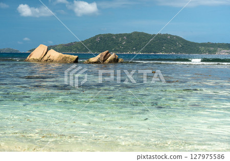 View of granite coastal rocks and ocean waves with distant islands on the horizon under cloudy 127975586
