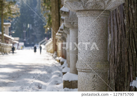 Winter scenery of a temple with a snow-covered approach and rows of stone lanterns 127975700