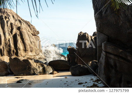 Picturesque rocks, granite boulders, and stones scatter over white Seychelles sand 127975799