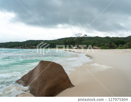 A granite boulder rests at the shoreline of La Digue island in Seychelles 127975804