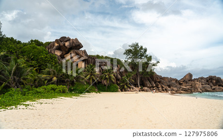 Granite cliffs rise above palm trees on the beach of La Digue island in Seychelles Granite cliffs rise above palm trees on the beach of La Digue island in Seychelles 127975806