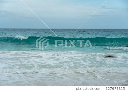 Ocean wave curls with white foam and turquoise body near the coast of La Digue, Seychelles 127975815