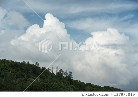 Towering cumulus clouds rise above tropical forest on La Digue island in Seychelles Towering cumulus clouds rise above tropical forest on La Digue island in Seychelles 127975819