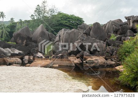 Tropical beach meets a shallow swamp surrounded by granite boulders and vegetation Tropical beach meets a shallow swamp surrounded by granite boulders and vegetation 127975828
