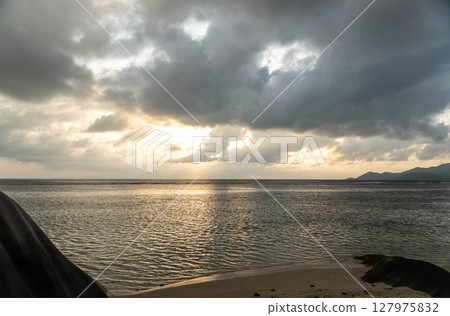 Granite rocks and sandy shoreline meet ocean waves on La Digue, Seychelles 127975832