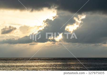 Cloud layers above calm sea reflect soft light at dusk near La Digue island, Seychelles 127975835