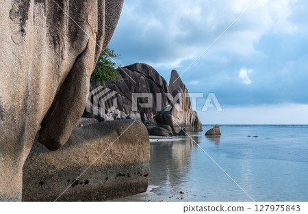 Granite rock formations rise above calm water on La Digue island, Seychelles Granite rock formations rise above calm water on La Digue island, Seychelles 127975843