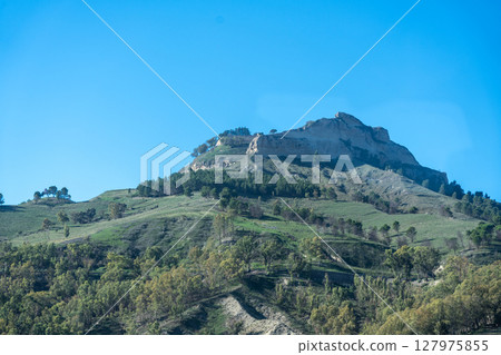 Scenic Sicilian landscape with mountain, trees and grassy hillside 127975855