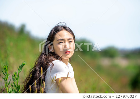 Young woman relaxing under blue sky 127976027