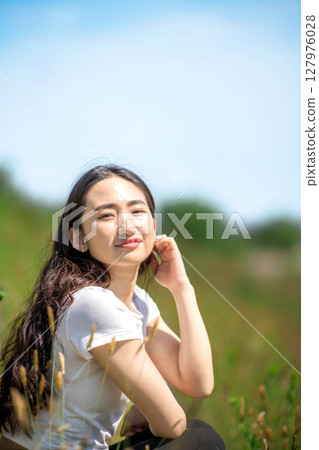 Young woman relaxing under blue sky Young woman relaxing under blue sky 127976028