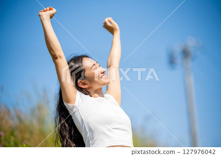 Young woman relaxing under blue sky 127976042