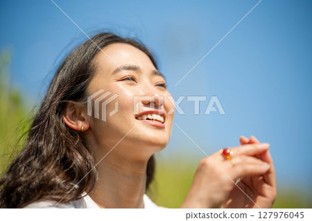 Young woman relaxing under blue sky Young woman relaxing under blue sky 127976045