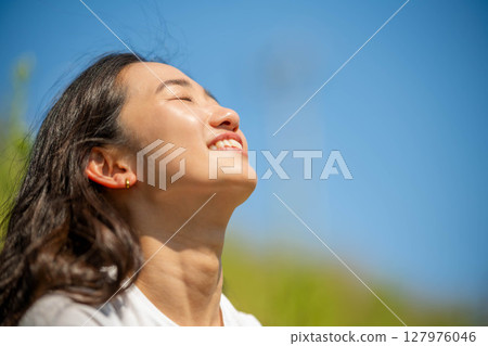 Young woman relaxing under blue sky Young woman relaxing under blue sky 127976046