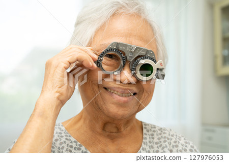 Asian senior woman wearing ophthalmic vision eye test and using optical trial frame. 127976053