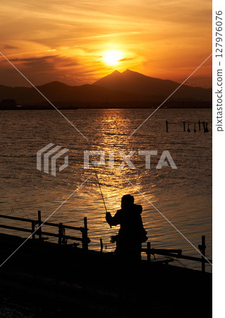 路亞釣魚、漁夫的剪影、霞浦湖和日落時的筑波山 127976076