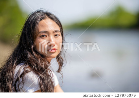 Young woman relaxing by the river Young woman relaxing by the river 127976079