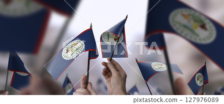 Belize flags in their hands on a blurred urban background 127976089